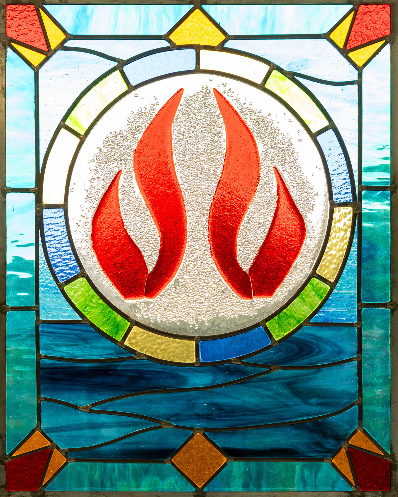 A stained-glass window of a flame, a symbol of the Holy Spirit, in our sanctuary